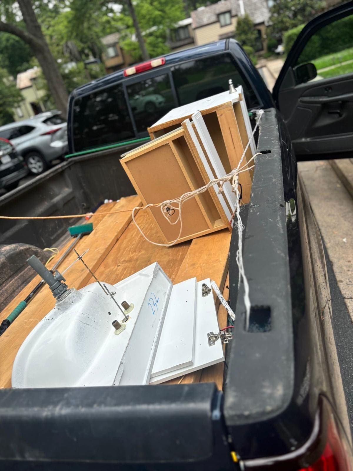 Bathroom sink, cabinet doors, and a vanity frame tied down in a pickup bed.