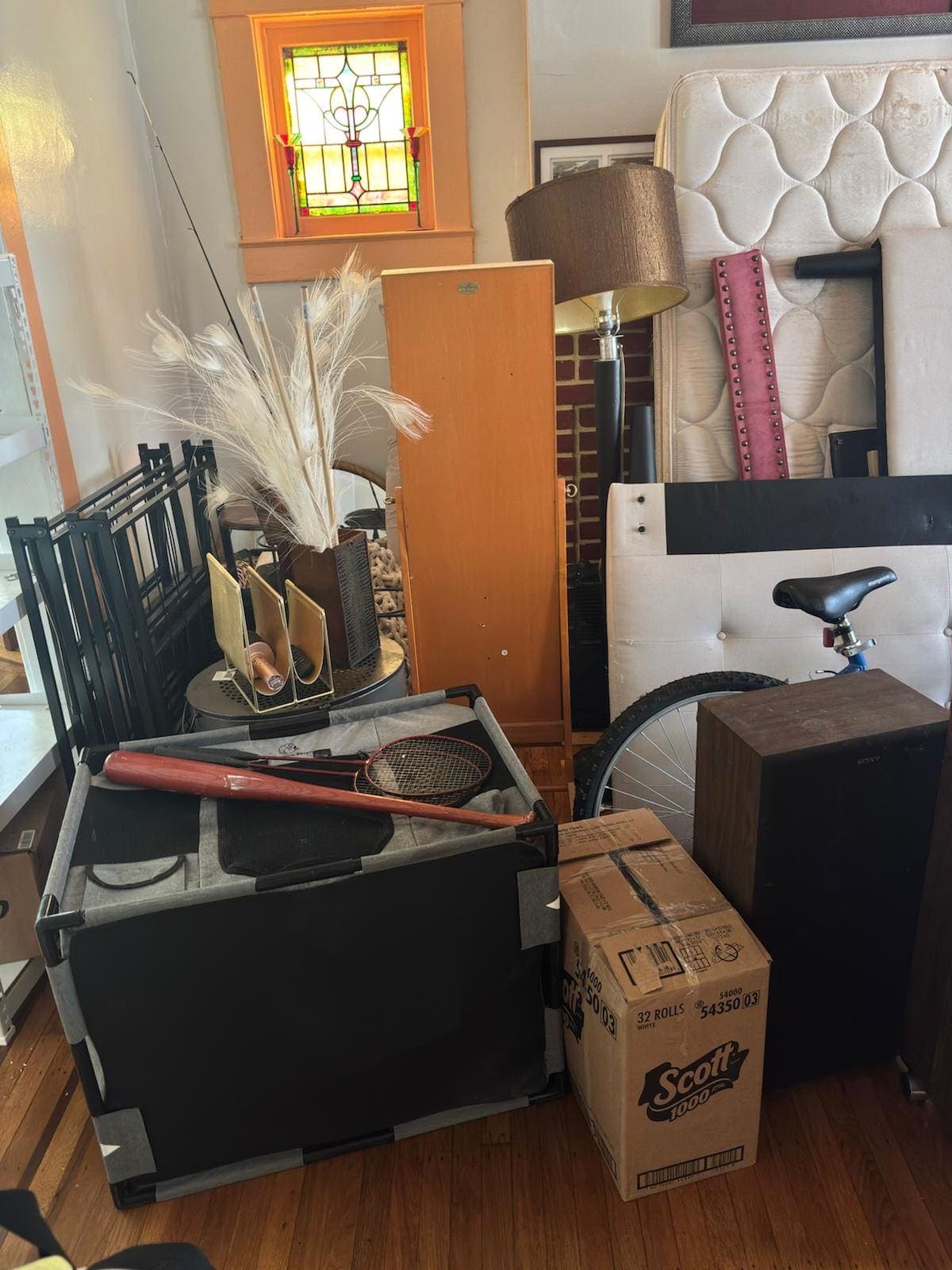 Room staged for a cleanout, with a mattress, lamp, bicycle, and household items.